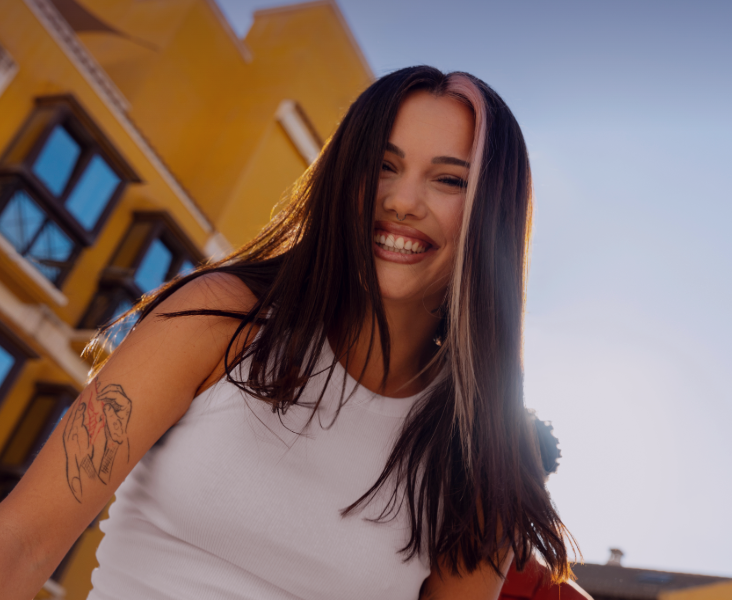 Mujer sonriente con edificio amarillo de fondo